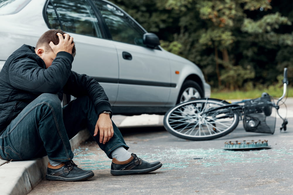 Man holding his head after a car and bicycle collision that caused a head injury