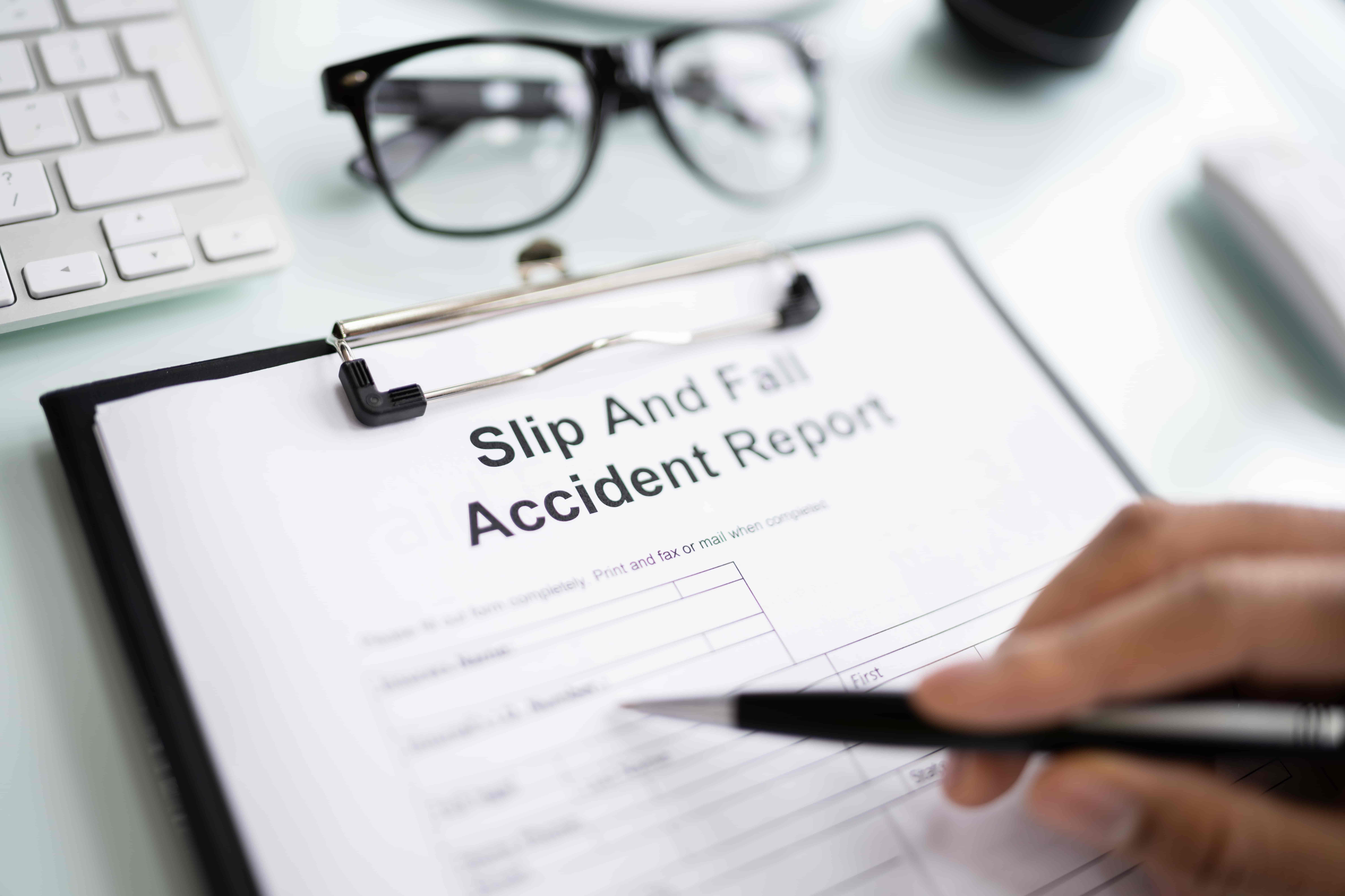 Person filling out a slip and fall accident report form after an injury.