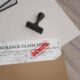 Insurance claim form stamped denied on desk with folder and rubber stamp.