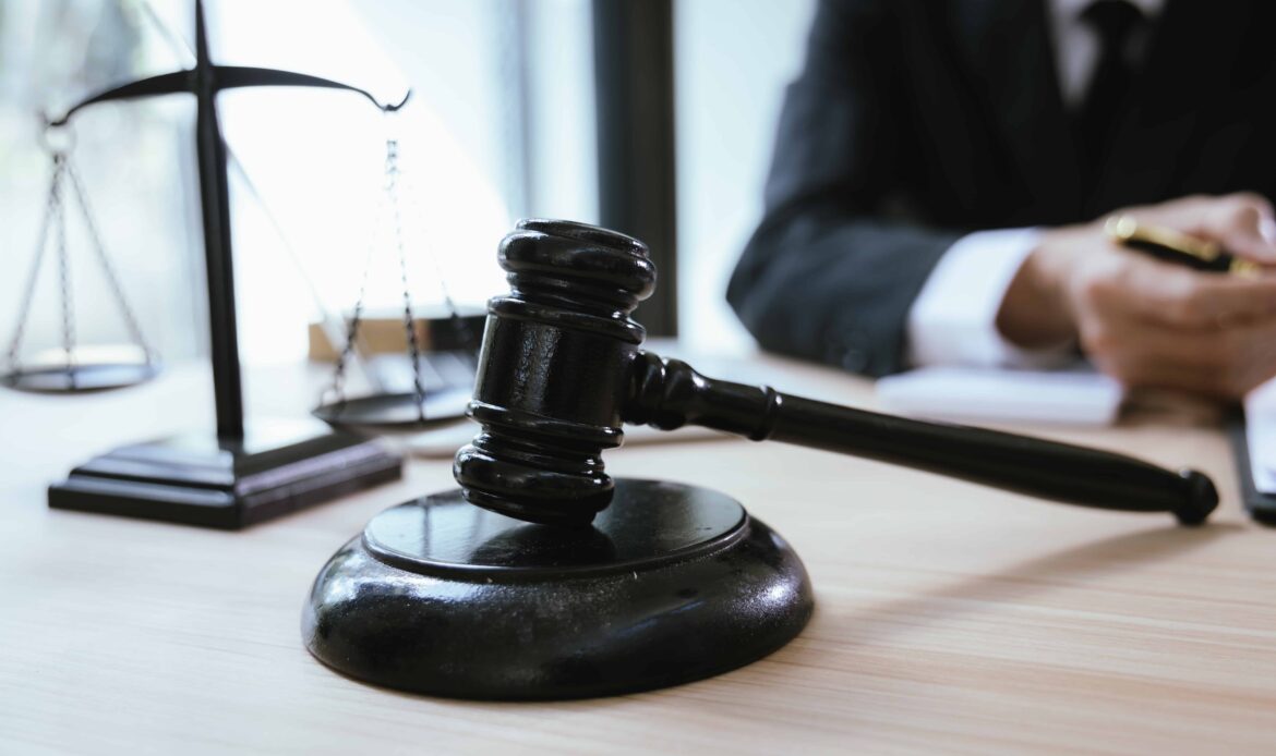 Judge’s gavel and justice scales on lawyer’s desk in courtroom or law office.