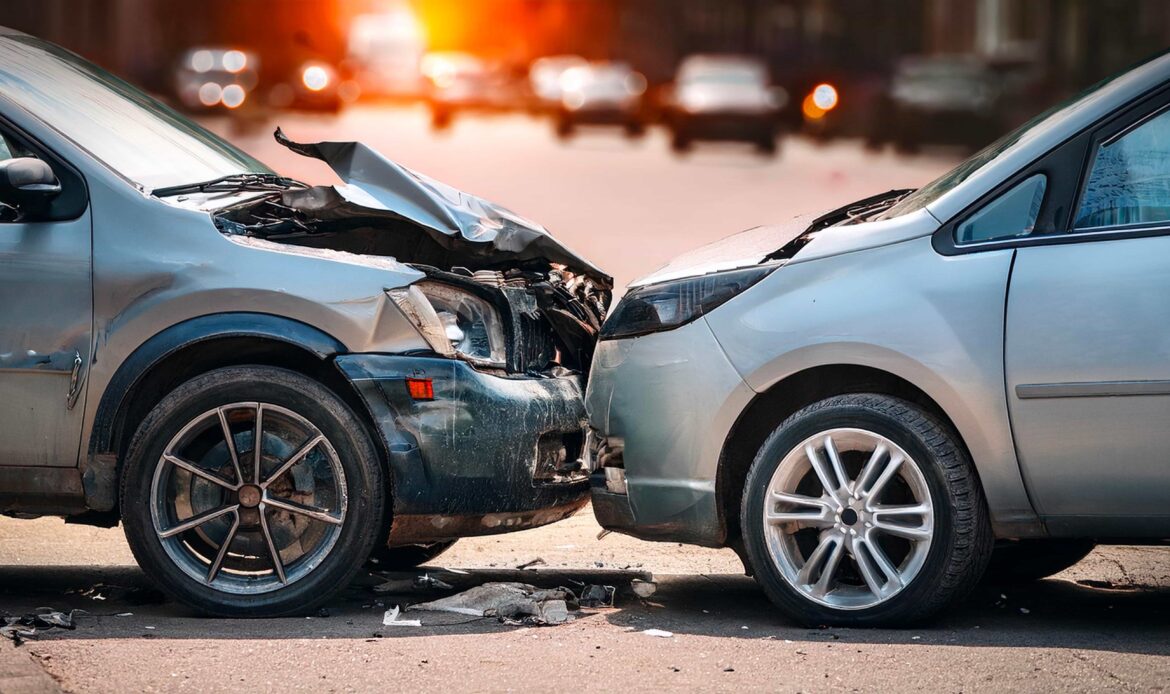Two damaged cars involved in a head-on collision on city street after car accident.
