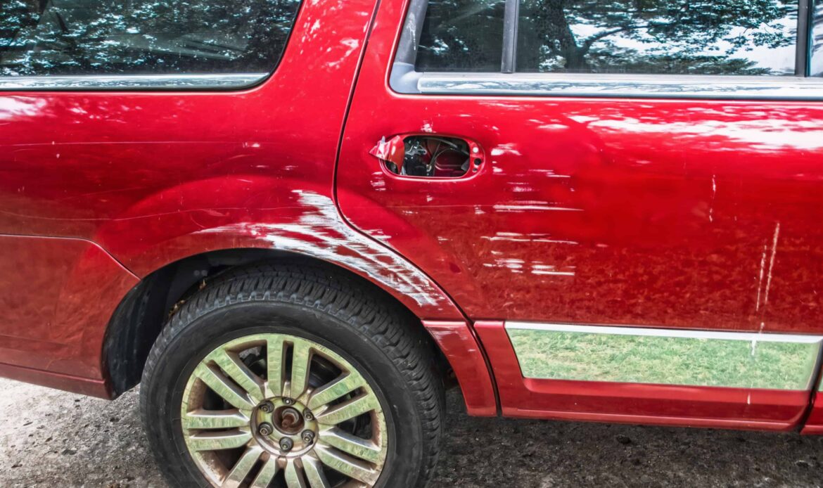 Red SUV with visible side damage and scratches from a collision or sideswipe accident.