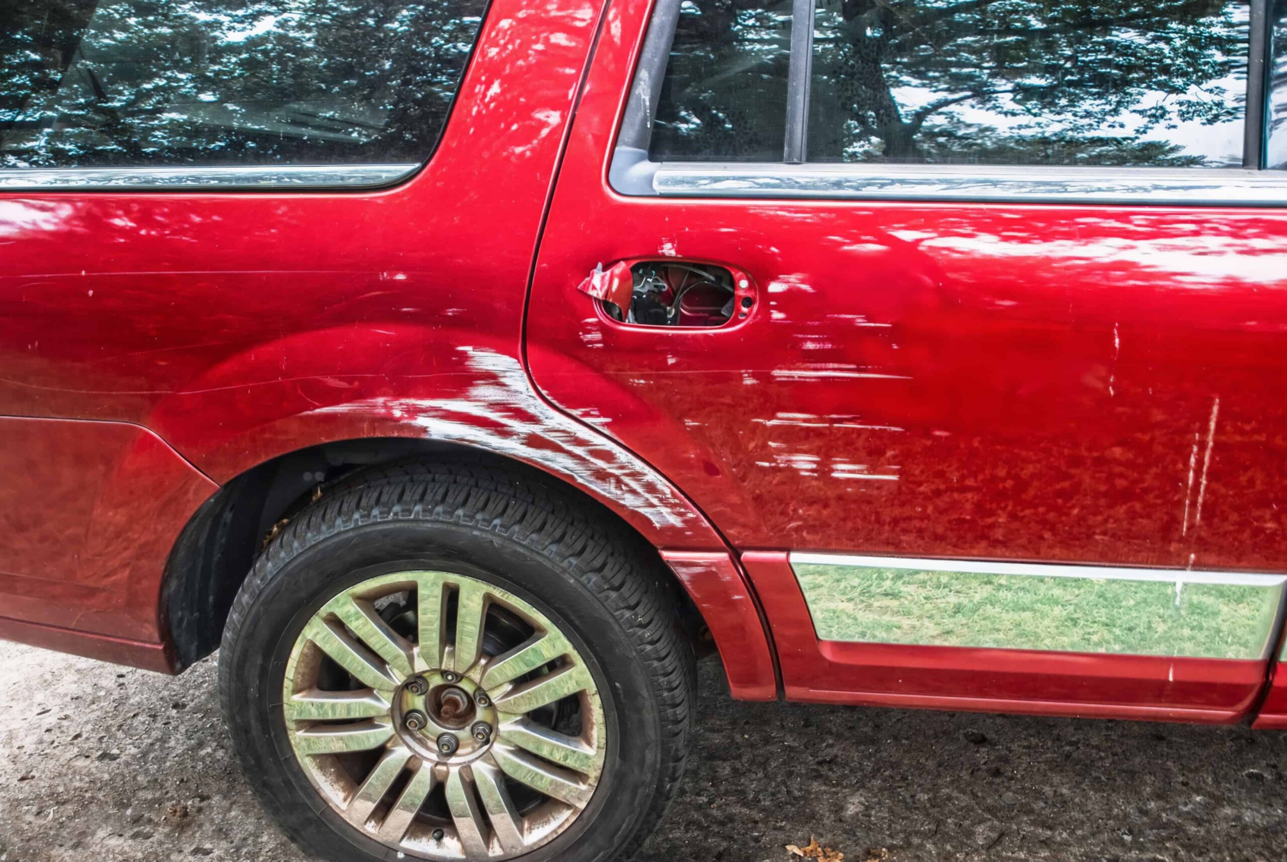 Red SUV with visible side damage and scratches from a collision or sideswipe accident. Red SUV with visible side damage and scratches from a collision or sideswipe accident.