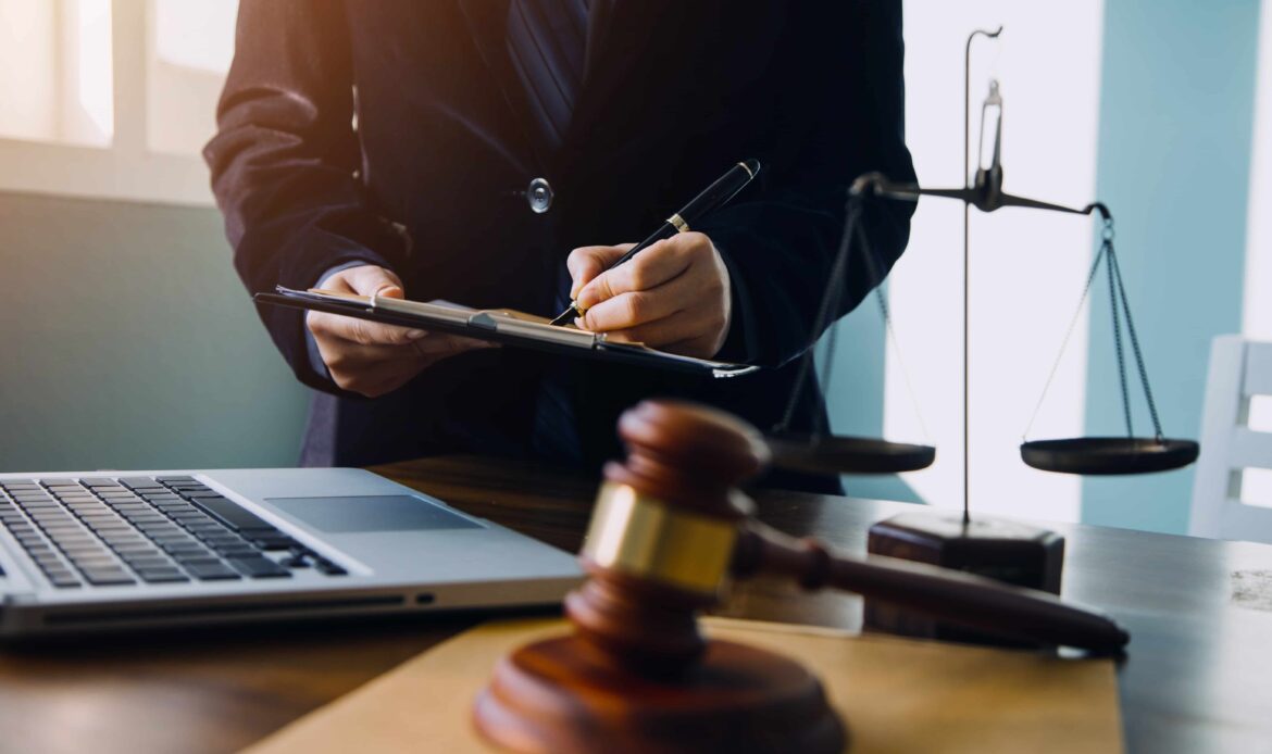 Lawyer reviewing legal documents at a desk with a gavel, justice scales, and laptop in a law office. Lawyer reviewing legal documents at a desk with a gavel, justice scales, and laptop in a law office.