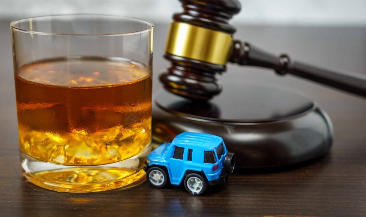 Glass of whiskey, toy car, and judge’s gavel symbolizing DUI and drunk driving legal consequences. Glass of whiskey, toy car, and judge’s gavel symbolizing DUI and drunk driving legal consequences.