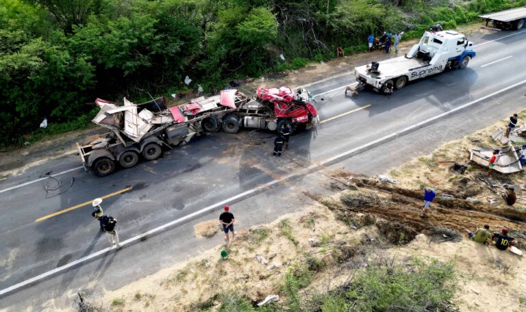 Aerial view of a serious semi-truck accident on a rural highway with emergency responders and tow trucks on scene.