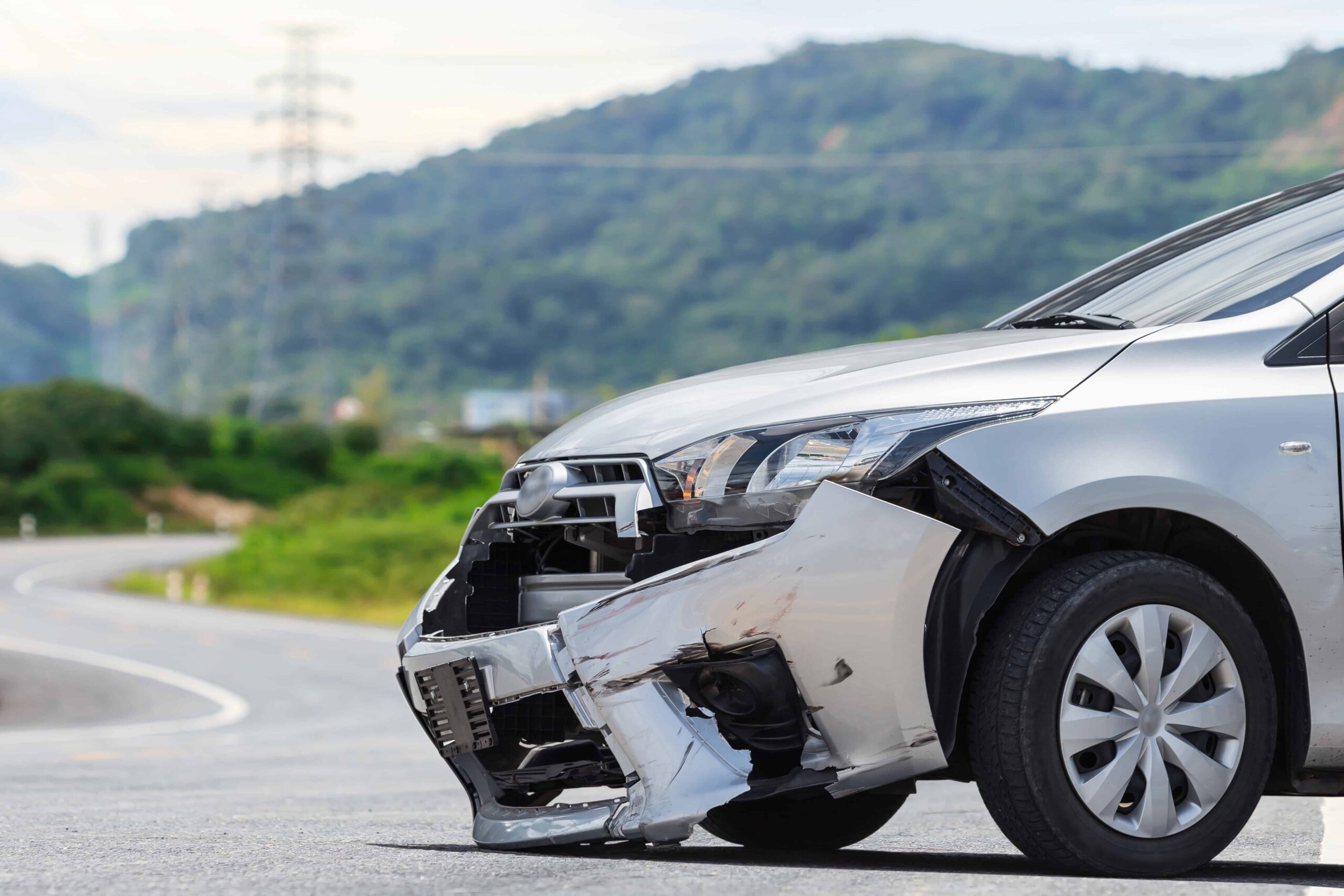 Front-end damage to a silver car after an accident on a rural road, representing auto collisions and vehicle crash claims.