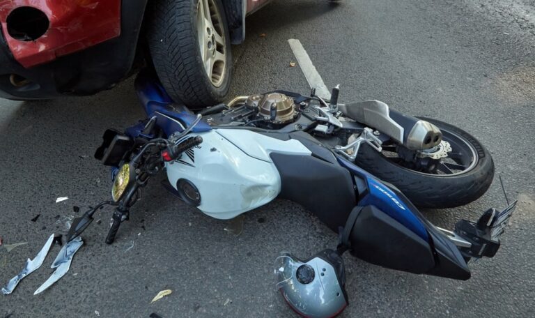 Motorcycle lying on roadway after collision with passenger vehicle