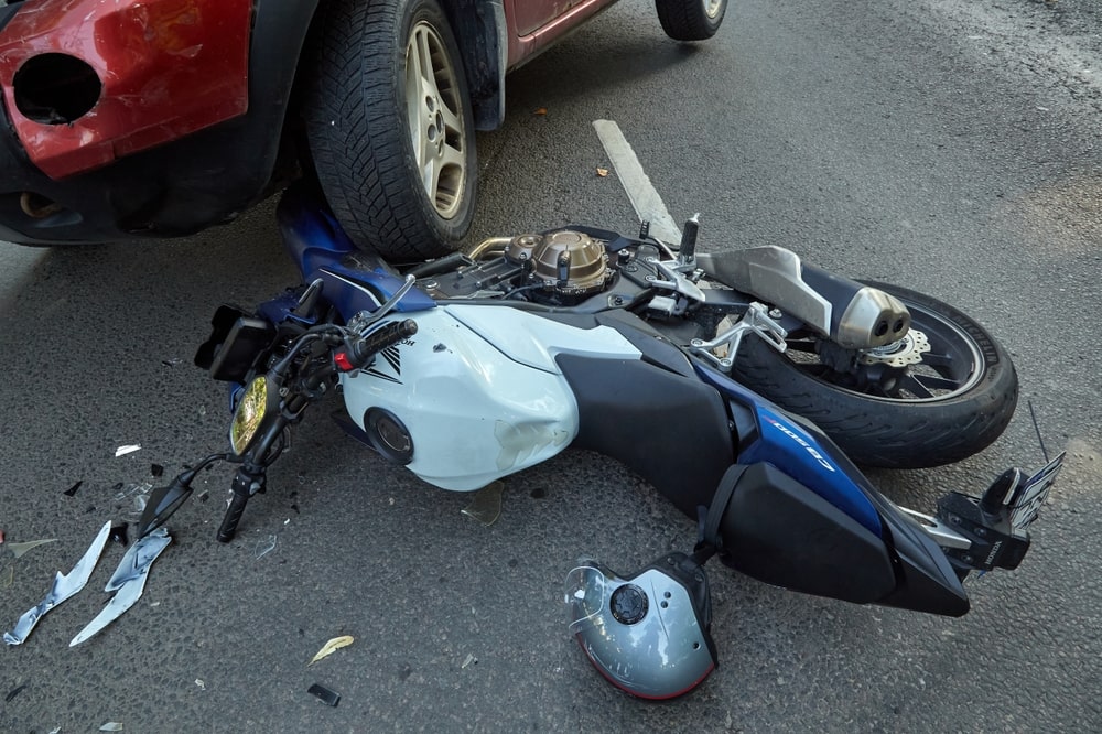 Motorcycle lying on roadway after collision with passenger vehicle