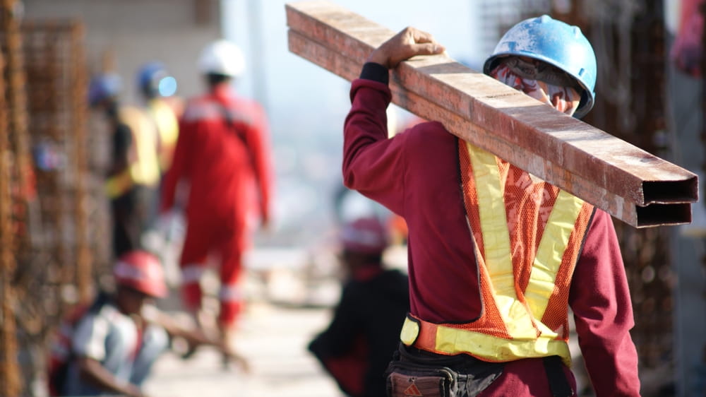 Construction worker carrying steel beam illustrating liability risks on Austin construction site