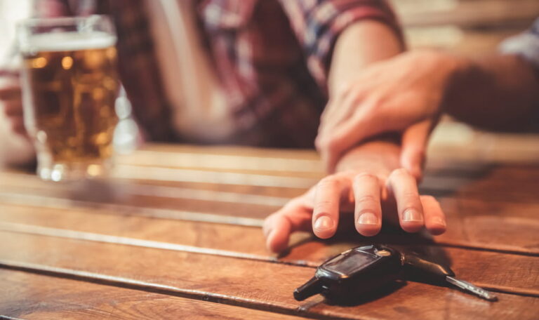 Bar patron reaching for car keys next to alcohol illustrating dram shop liability in Colorado