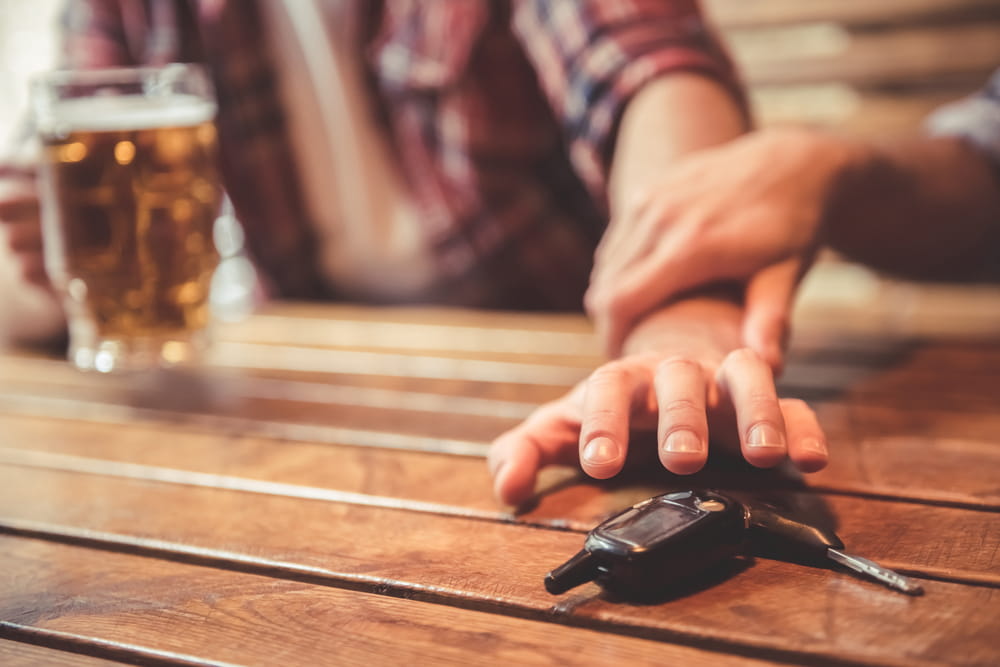Bar patron reaching for car keys next to alcohol illustrating dram shop liability in Colorado