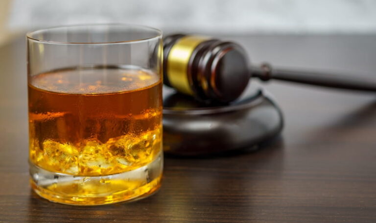 Alcohol drink next to judge gavel representing punitive damages for drunk driving in Colorado