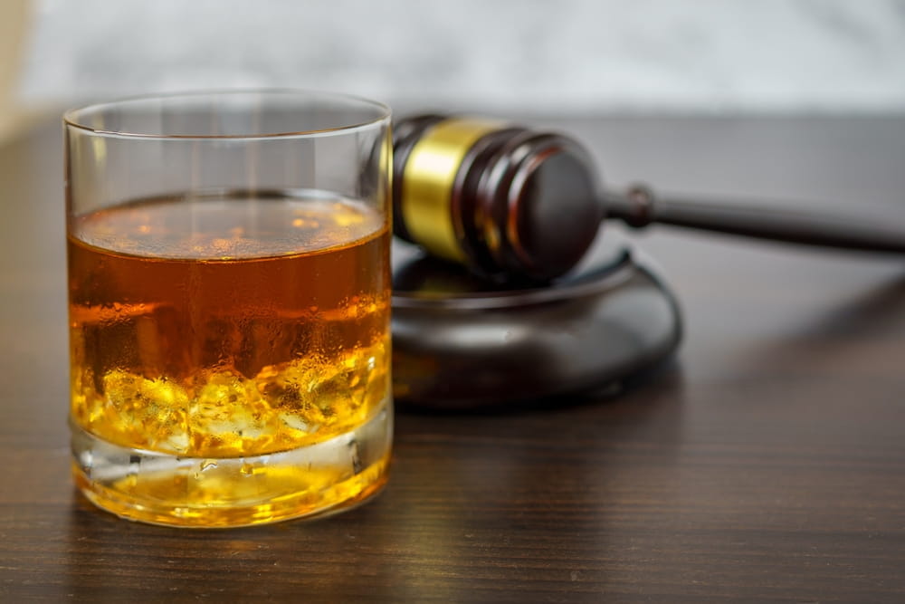 Alcohol drink next to judge gavel representing punitive damages for drunk driving in Colorado