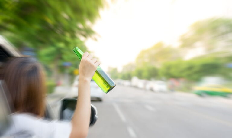 Underage driver holding alcohol bottle out of car window before DUI accident in Colorado