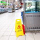 Caution wet floor sign in a grocery store aisle highlighting potential slip and fall hazard for customers