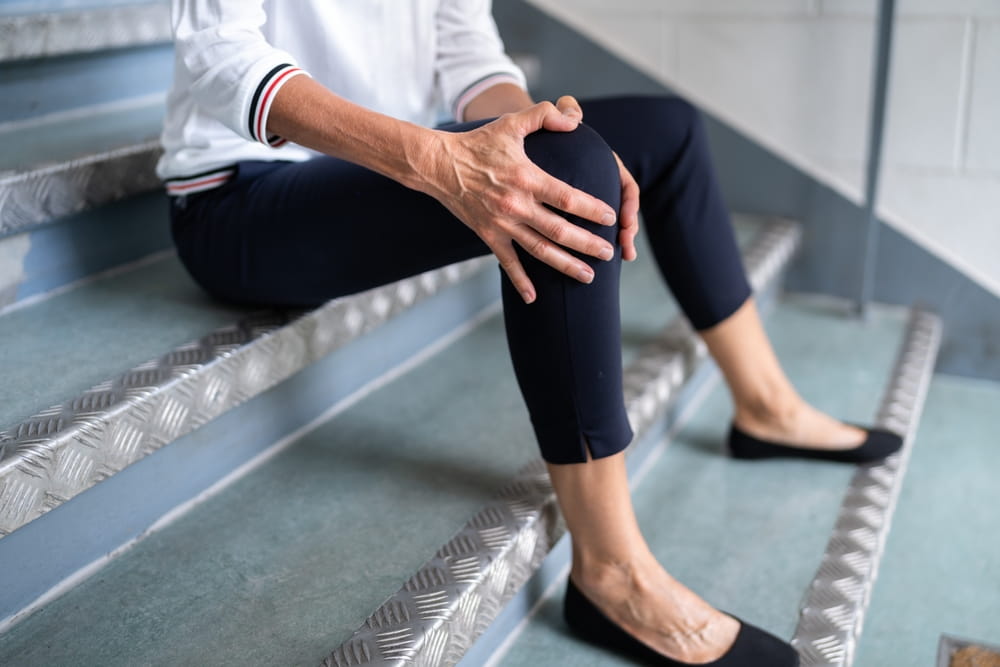 Person holding injured knee after slipping and falling, illustrating common injuries in grocery store accidents