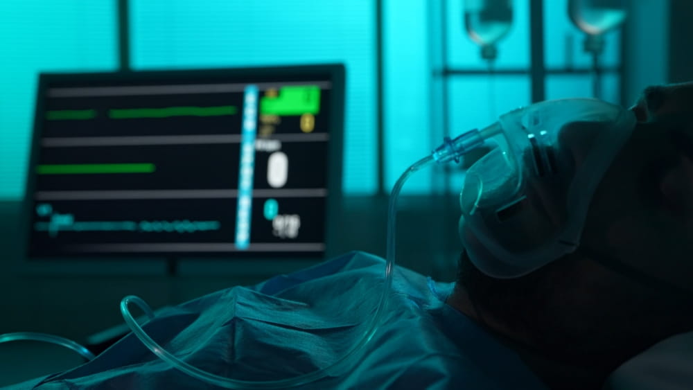 Hospital patient on a ventilator with vital signs monitor after a severe brain injury