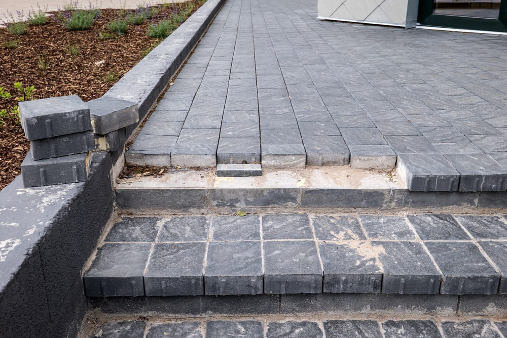 Uneven pavers and cracked steps representing a dangerous condition on commercial property