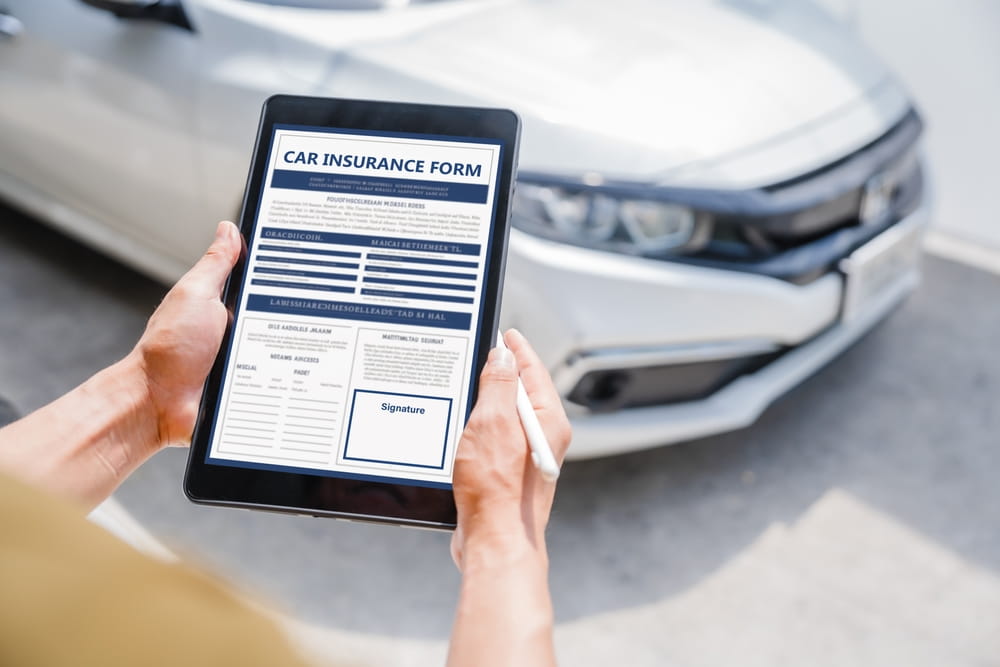 Filing a Car Insurance Claim After an Accident Person filling out a car insurance claim form on a tablet after an accident