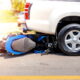 Motorcycle wreckage and dropped helmet at a crosswalk after a crash