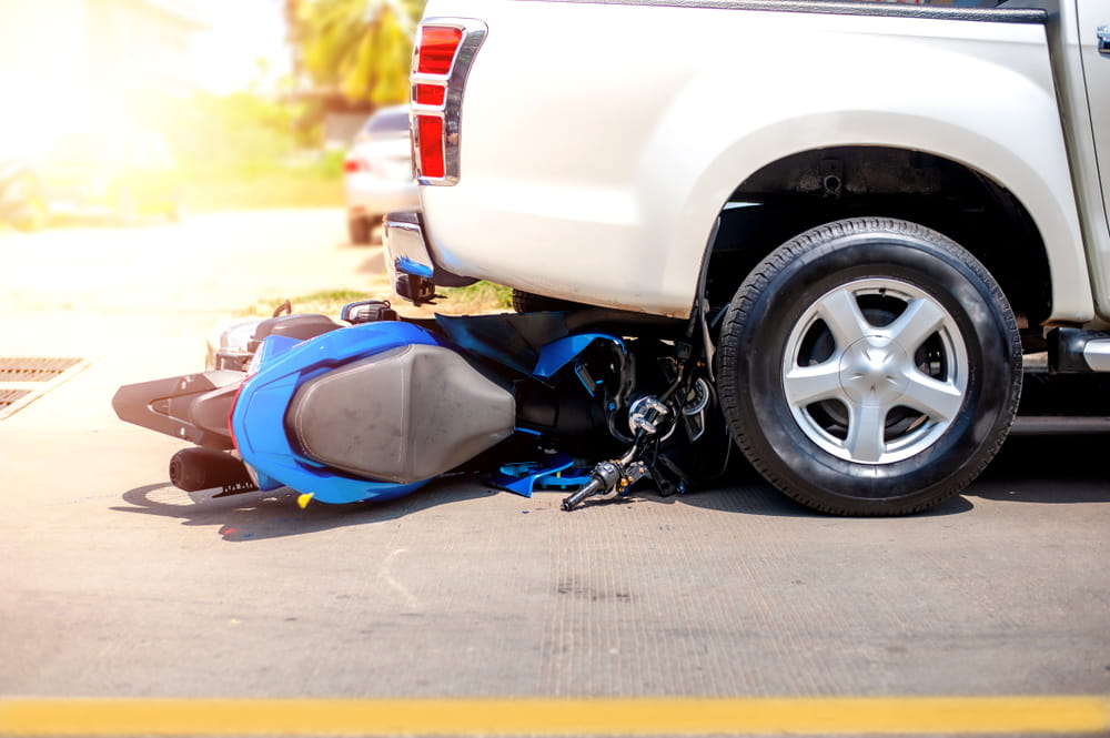 Motorcycle wreckage and dropped helmet at a crosswalk after a crash