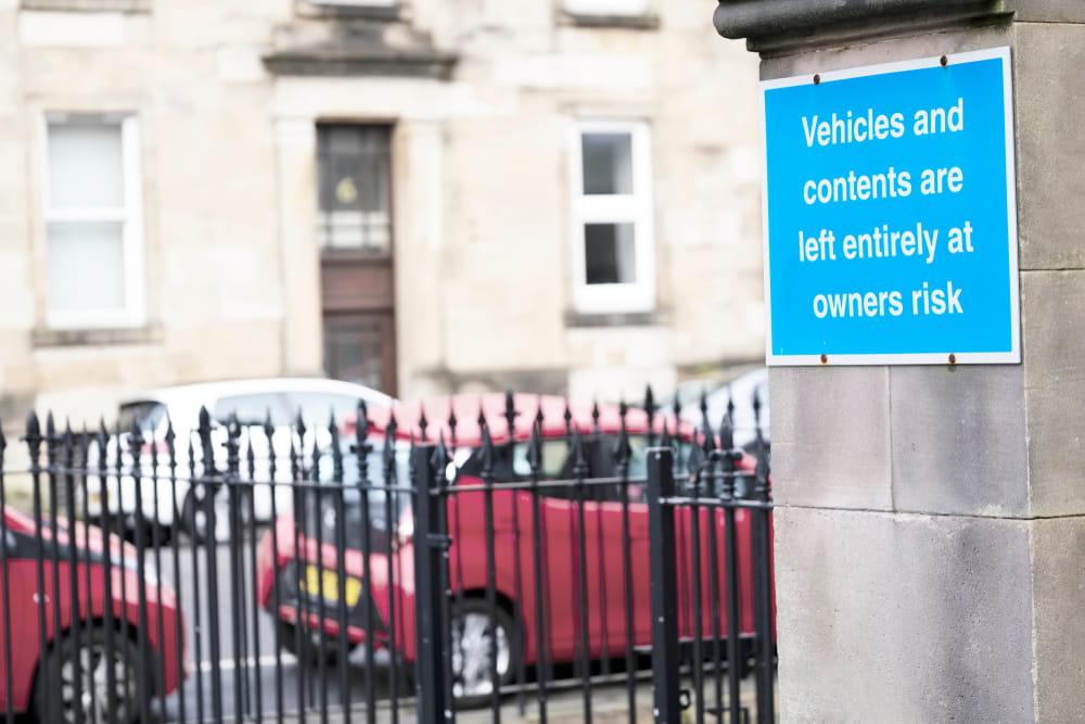 Sign stating vehicles are left at owner's risk outside a property