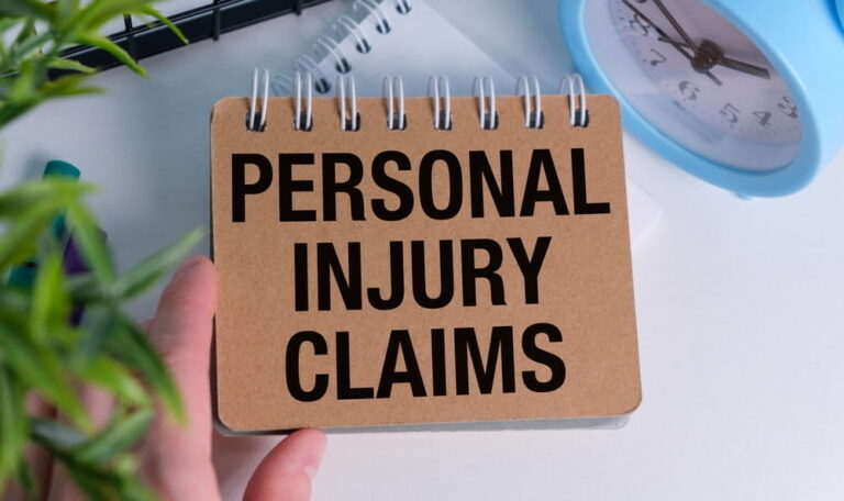 Hand holding a notepad reading "Personal Injury Claims"