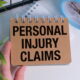 Hand holding a notepad reading "Personal Injury Claims"