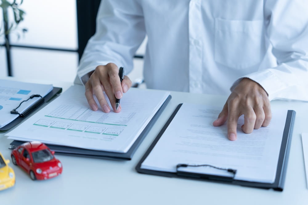 Person reviewing car accident claim documents and records at a desk