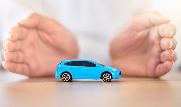 Hands framing a toy car representing insurance coverage