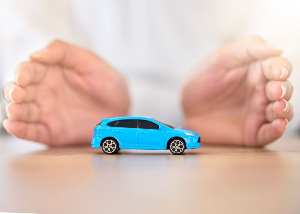 Rideshare Insurance Coverage Hands framing a toy car representing insurance coverage