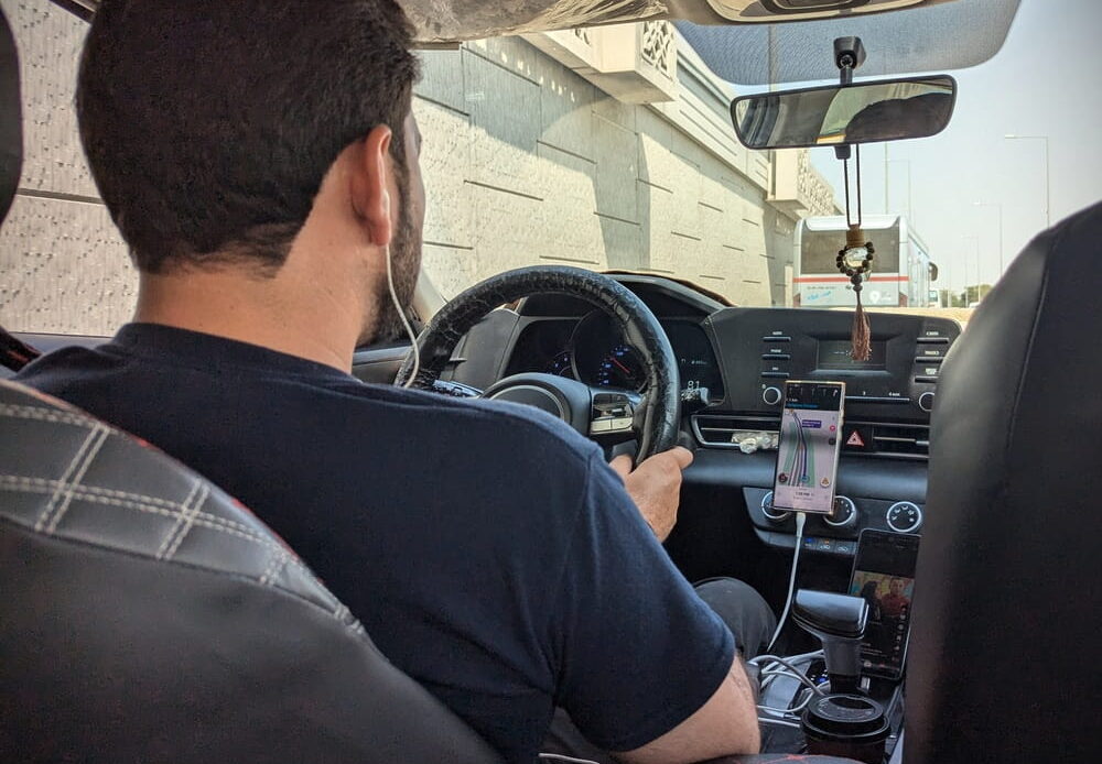 Rideshare driver with phone mounted on the dashboard during a trip