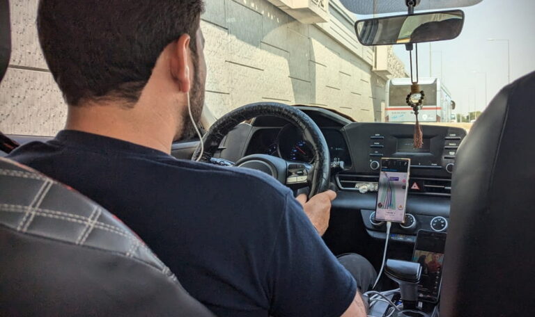 Rideshare driver with phone mounted on the dashboard during a trip